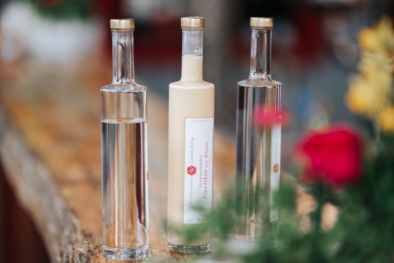 Drei Alkoholflaschen stehen auf einem Holztisch.