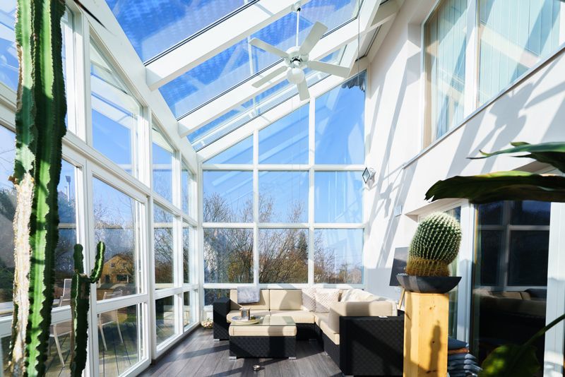 Ein Wohnzimmer mit vielen Fenstern und einem Deckenventilator.