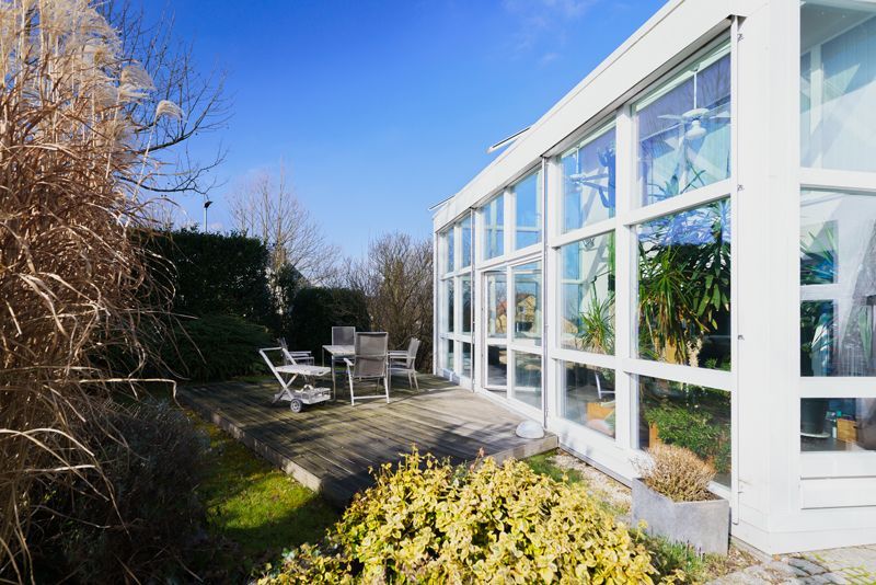 Ein großes weißes Gebäude mit vielen Fenstern und einer Terrasse davor.