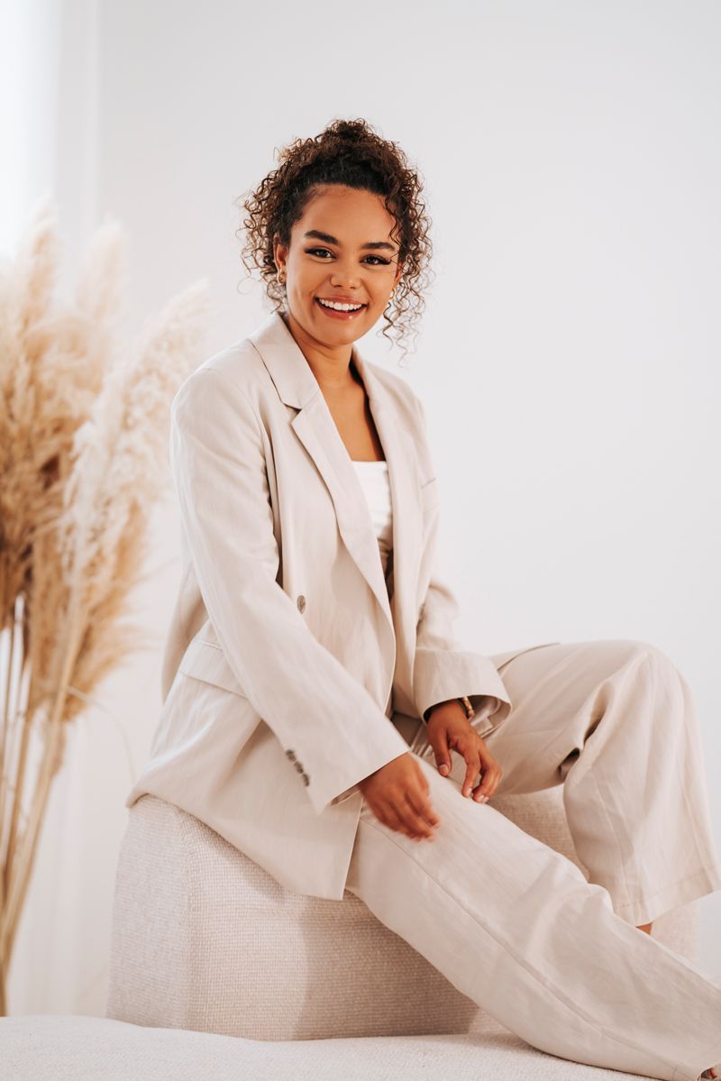 Eine Frau in einem weißen Anzug sitzt auf einem Felsen.