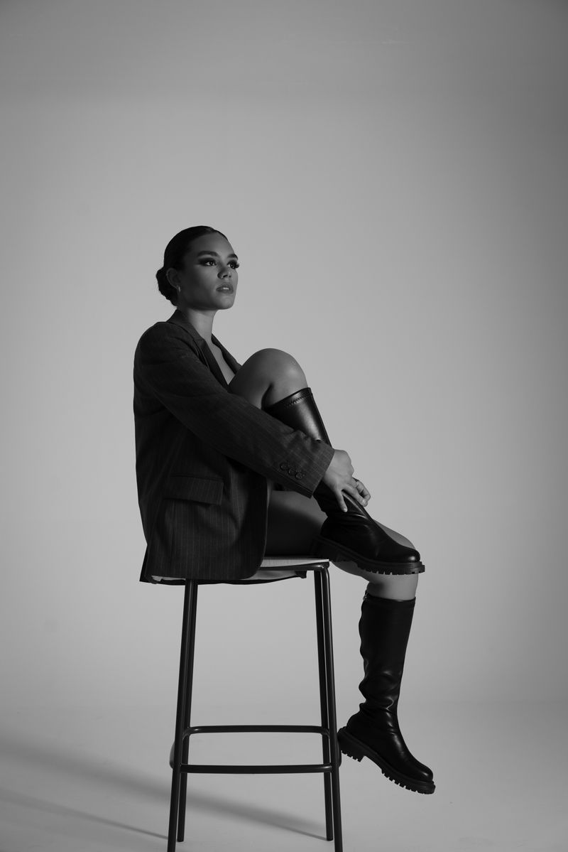 Eine Frau sitzt mit übereinandergeschlagenen Beinen auf einem Hocker.