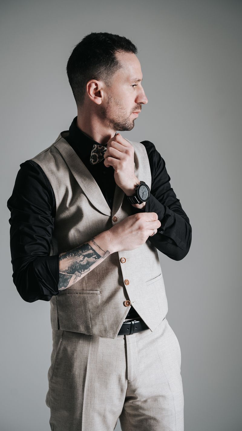 Ein Mann im Anzug richtet seine Krawatte und trägt dabei eine Uhr.