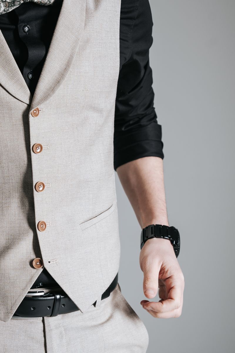 Ein Mann mit Weste und schwarzem Hemd trägt eine Uhr am Handgelenk.