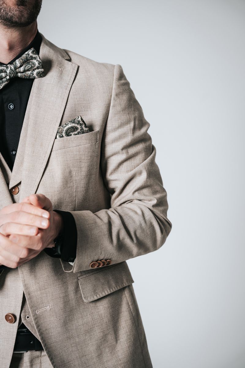 Ein Mann in Anzug und Fliege richtet seine Manschetten.