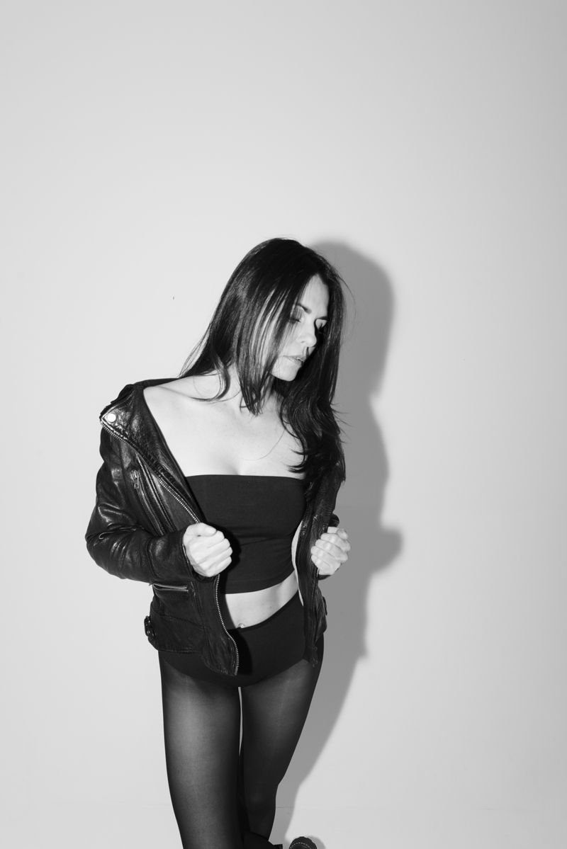 Ein Schwarzweißfoto einer Frau, die eine Lederjacke und Strumpfhosen trägt.
