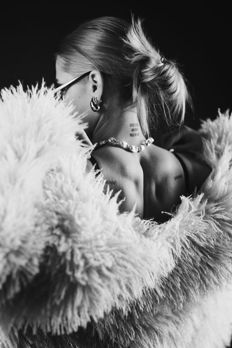 Ein Schwarzweißfoto einer Frau mit Brille und Pelzmantel.