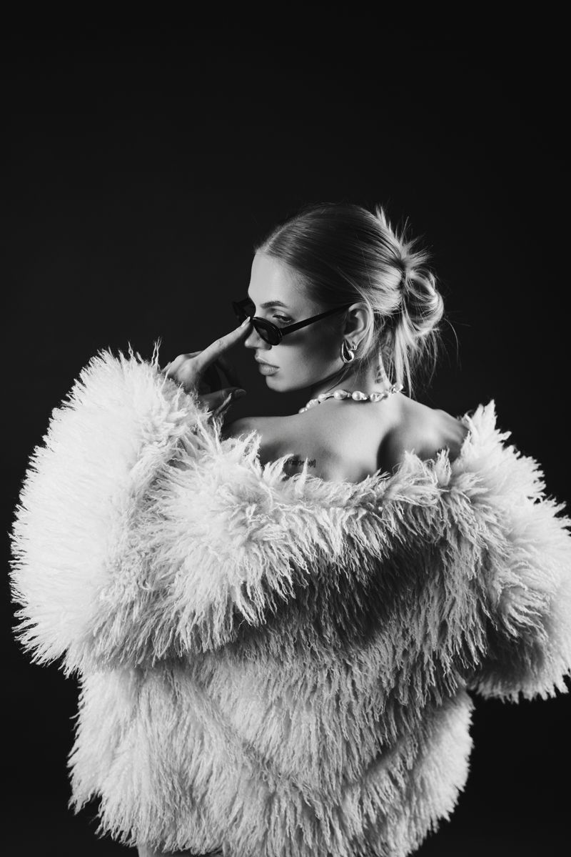 Ein Schwarzweißfoto einer Frau, die einen Pelzmantel und eine Sonnenbrille trägt.