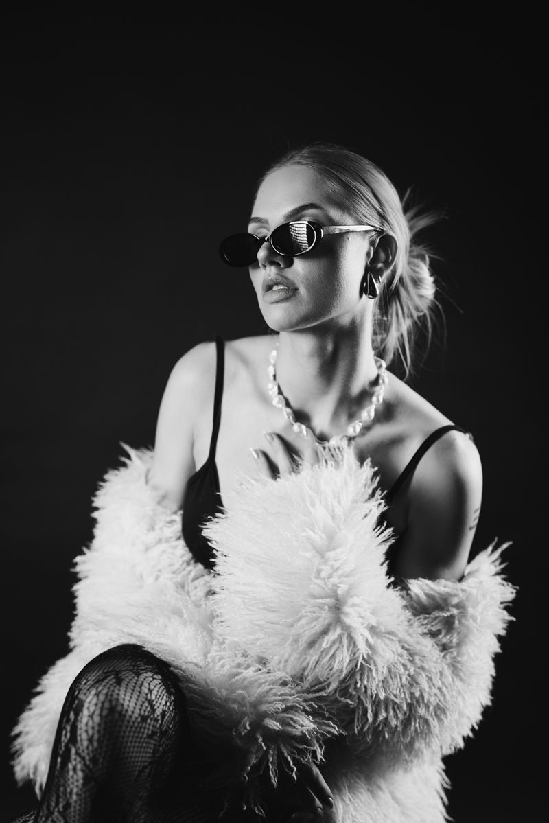 Ein Schwarzweißfoto einer Frau mit Sonnenbrille und Pelzmantel.