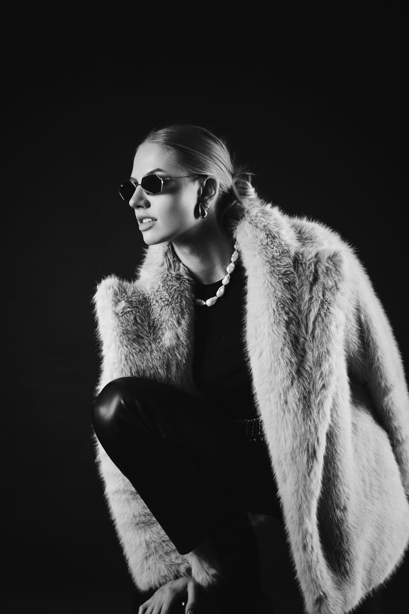 Ein Schwarzweißfoto einer Frau, die einen Pelzmantel und eine Sonnenbrille trägt.