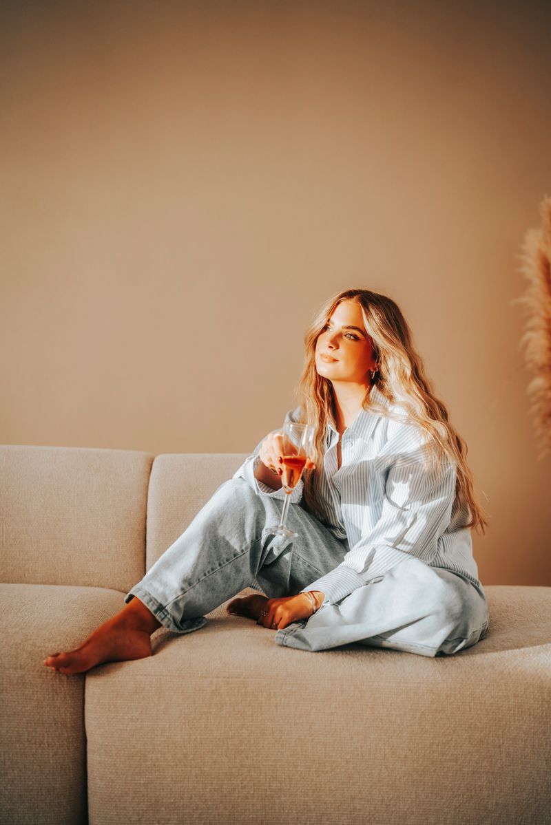 Eine Frau sitzt mit einem Glas Wein auf einem Sofa.