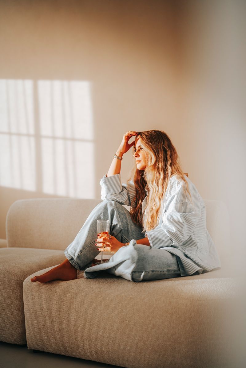 Eine Frau sitzt mit einem Glas Wein auf einem Sofa.