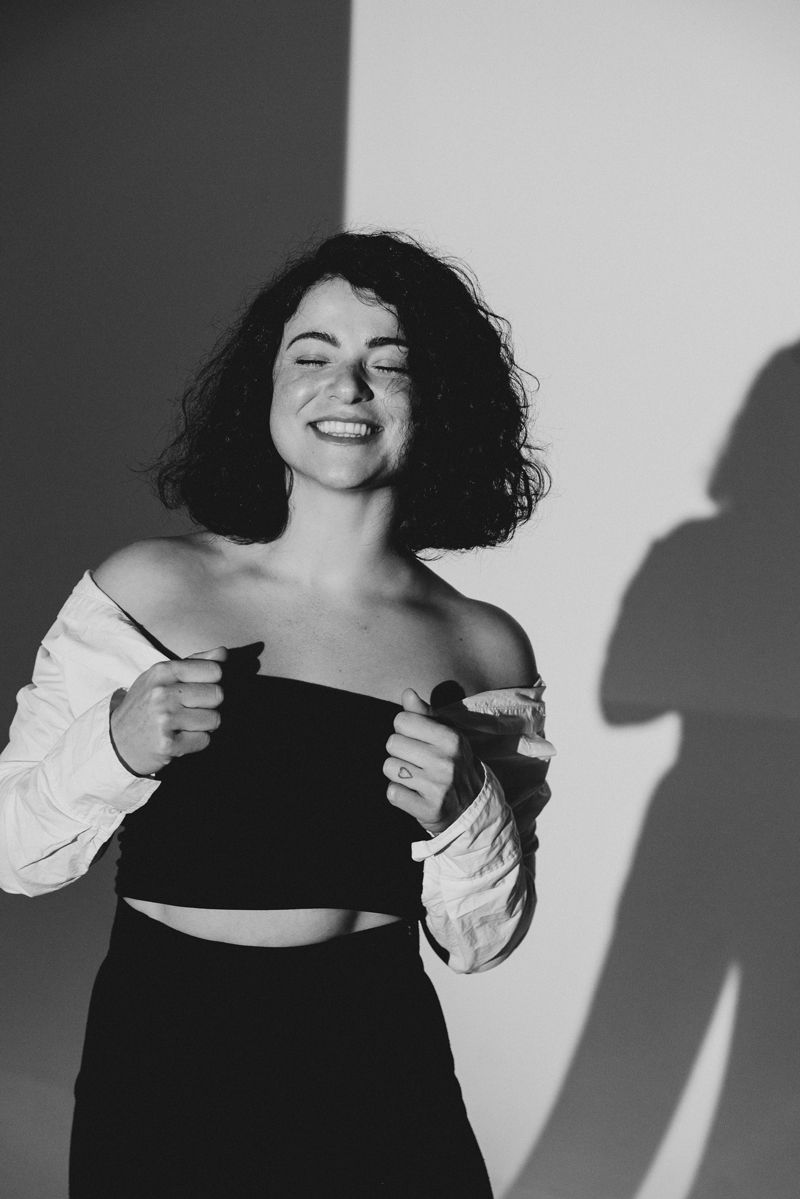 Ein Schwarzweißfoto einer Frau, die vor einer weißen Wand steht.