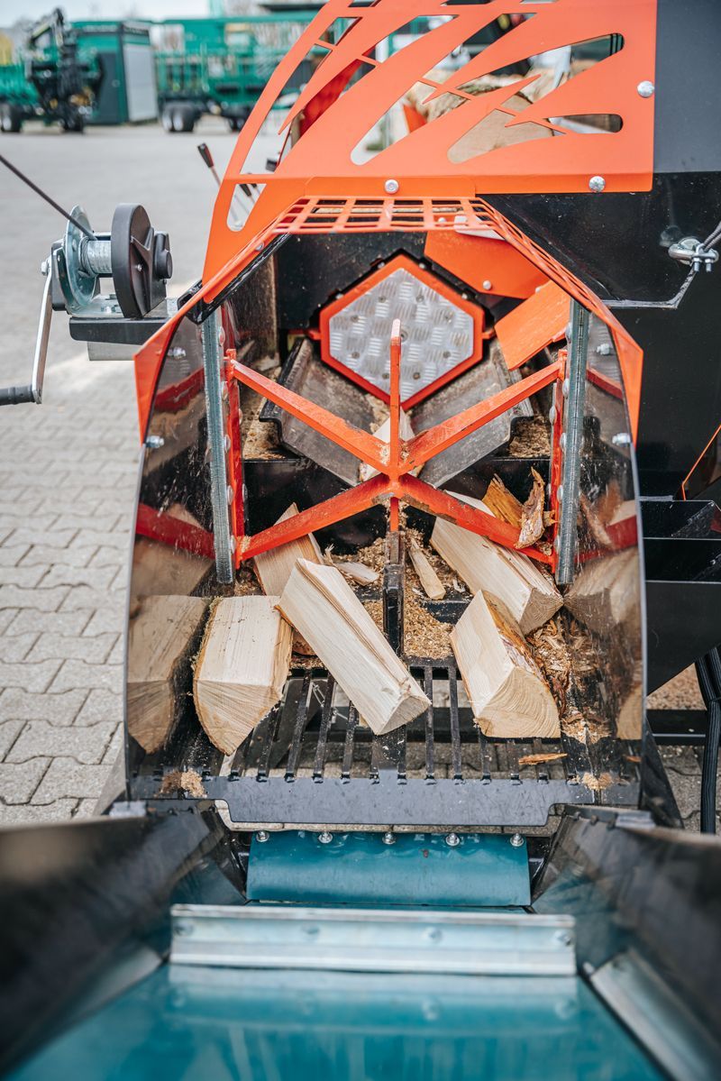 Auf einem gepflasterten Gehweg steht eine Maschine, die Holz schneidet.