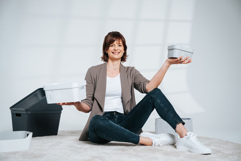 Eine Frau sitzt auf dem Boden und hält eine Schachtel in der Hand.