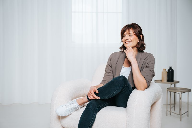 Eine Frau sitzt mit übereinandergeschlagenen Beinen auf einem Stuhl.