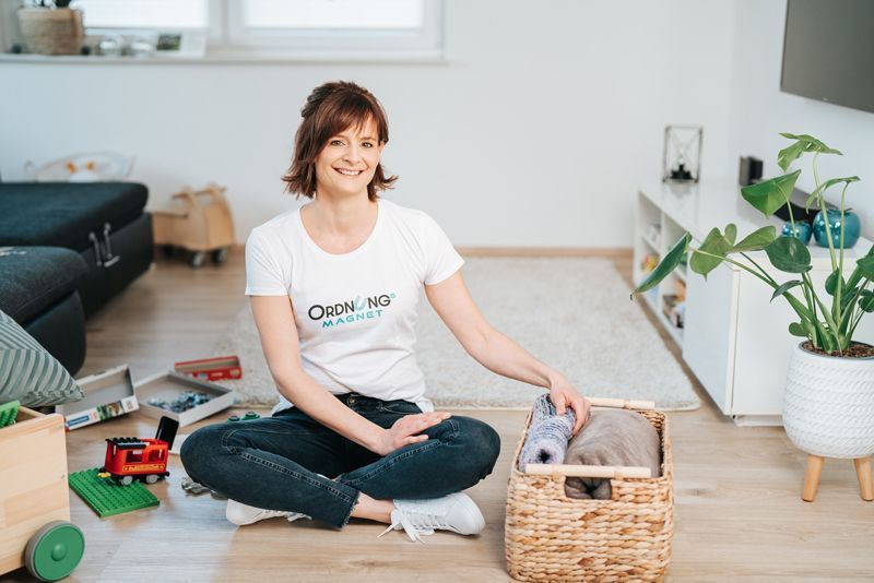Eine Frau sitzt in einem Wohnzimmer auf dem Boden.
