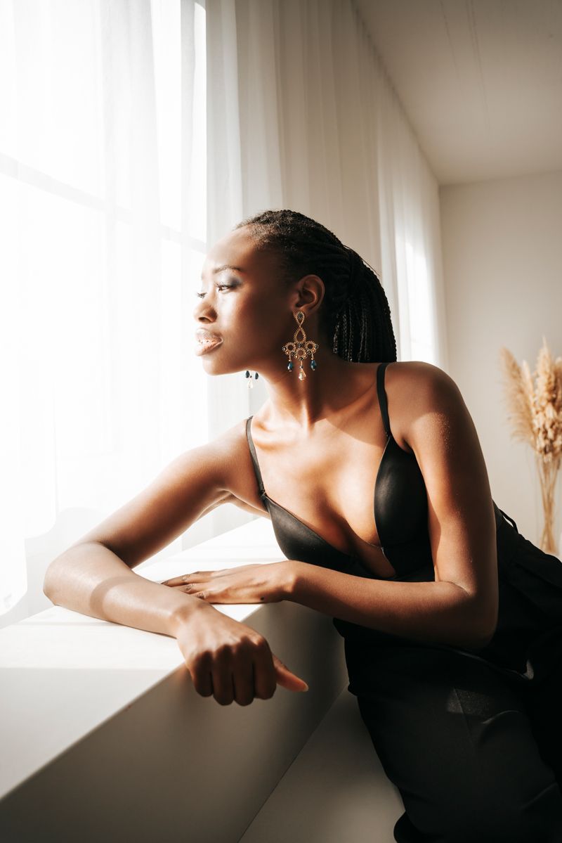 Eine Frau in einem schwarzen Kleid lehnt auf einem Fensterbrett.