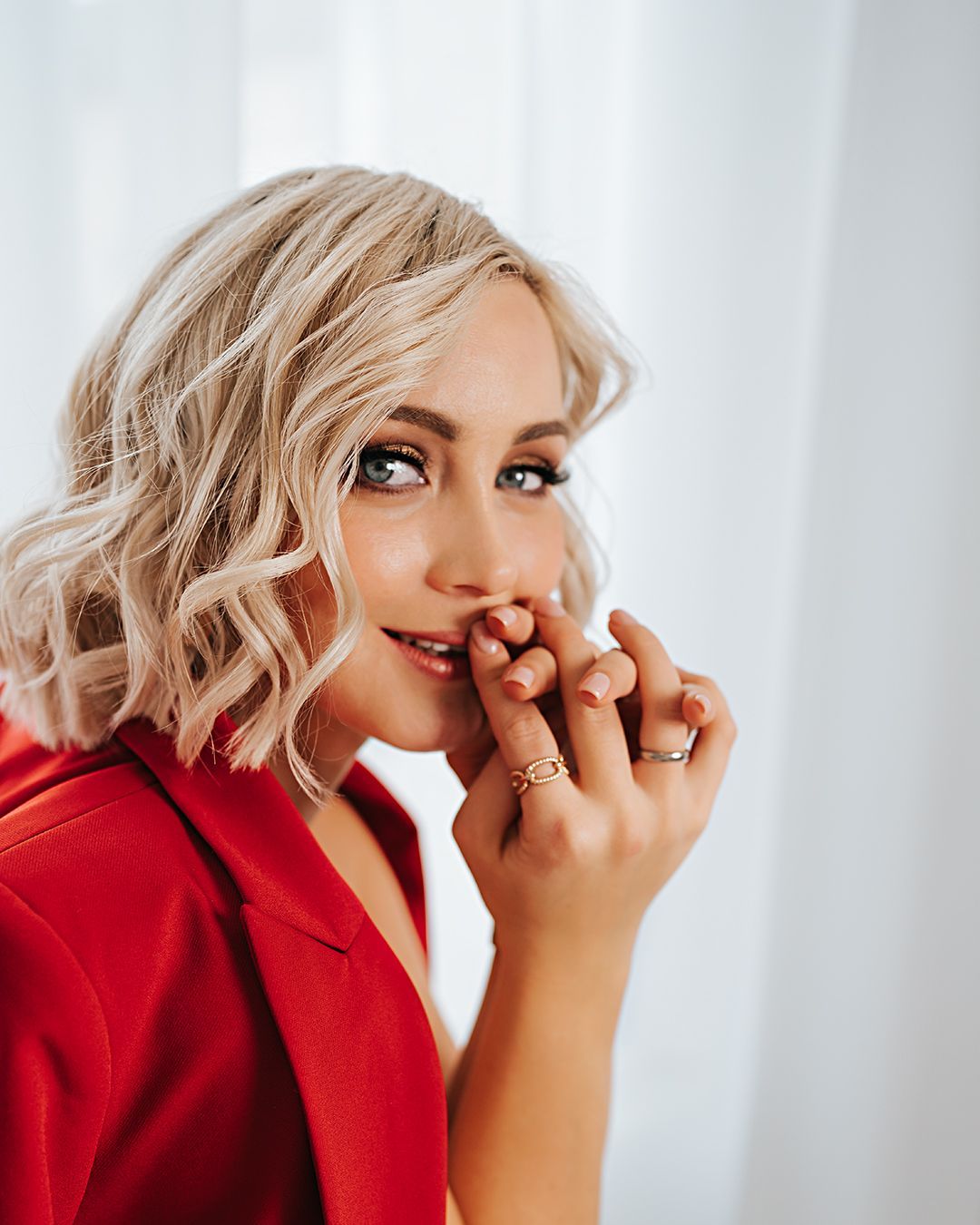 Eine Frau in einer roten Jacke bedeckt ihren Mund mit den Händen.