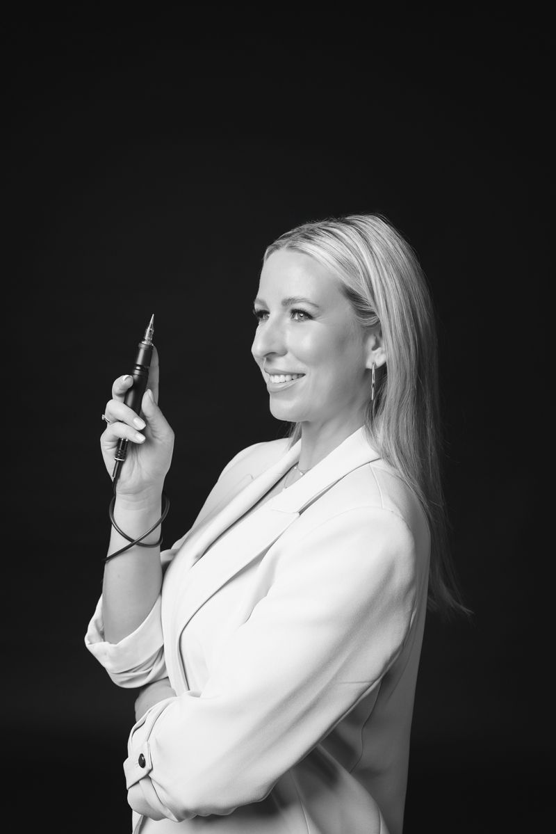 Eine Frau in einer weißen Jacke hält einen Stift in der Hand.