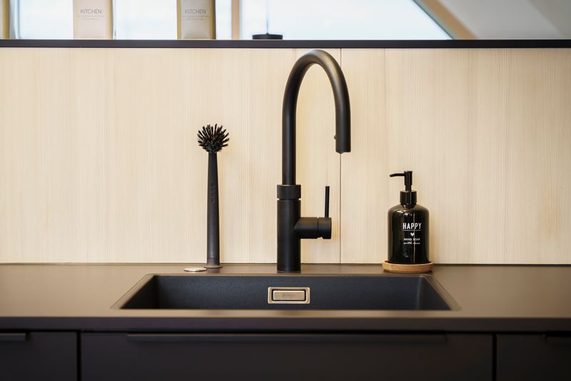Eine Küchenspüle mit einem schwarzen Wasserhahn und einem Seifenspender.