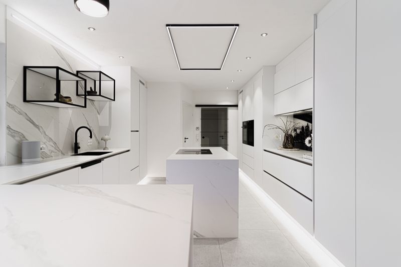 Eine Küche mit weißen Schränken und einer großen Insel in der Mitte.