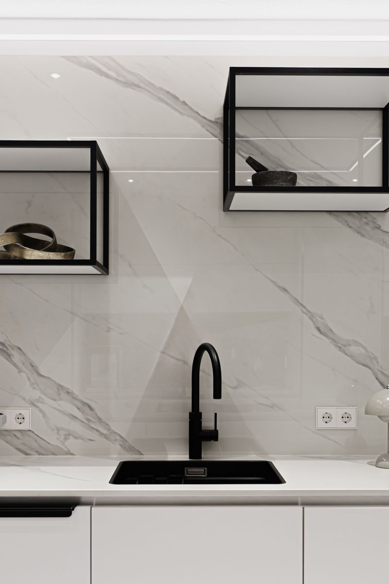 Eine Küche mit Spüle, Regalen und Marmorwand.