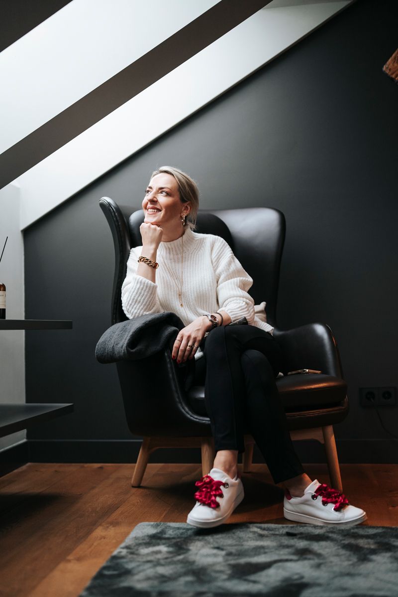 Eine Frau sitzt in einem Wohnzimmer auf einem Stuhl.