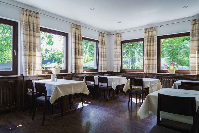 Ein Restaurant mit Tischen und Stühlen und vielen Fenstern