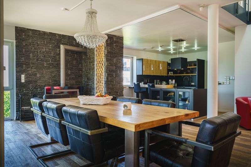 Ein Esstisch und Stühle in einem Haus mit einem Kronleuchter, der von der Decke hängt.