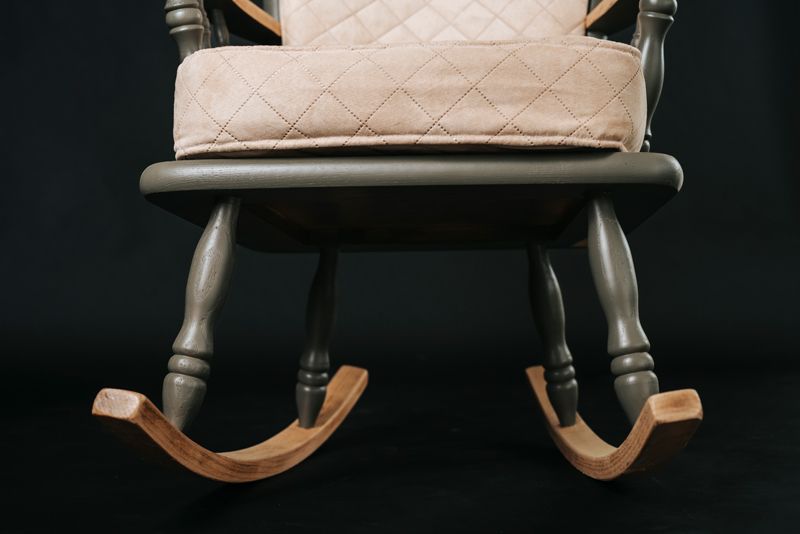 Ein Schaukelstuhl mit gestepptem Kissen auf schwarzem Hintergrund