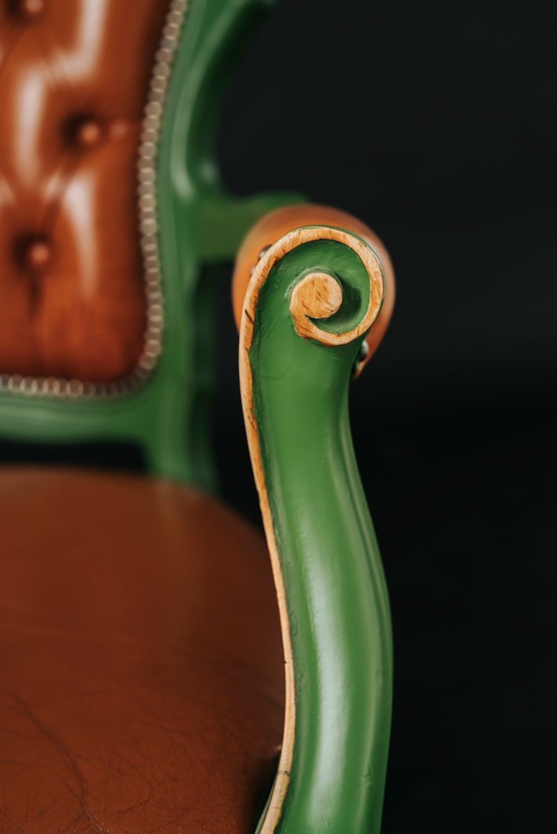 Eine Nahaufnahme eines grünen Stuhls mit einem braunen Kissen auf schwarzem Hintergrund.