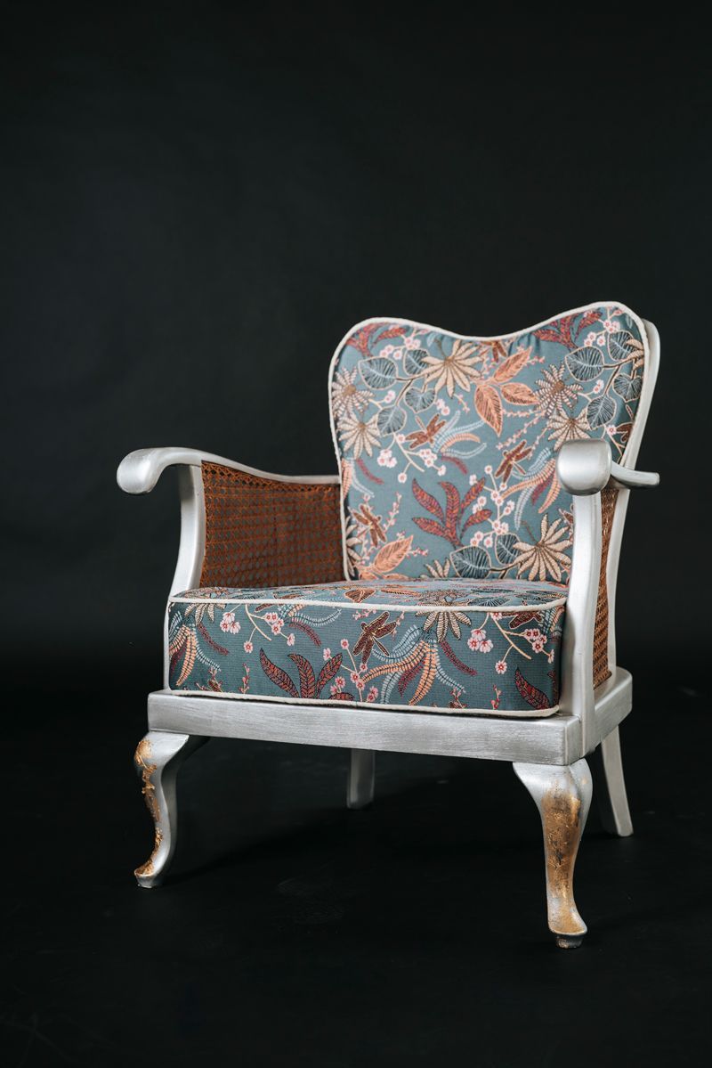 Auf einem schwarzen Hintergrund steht ein Stuhl mit einem Kissen mit Blumenmuster.