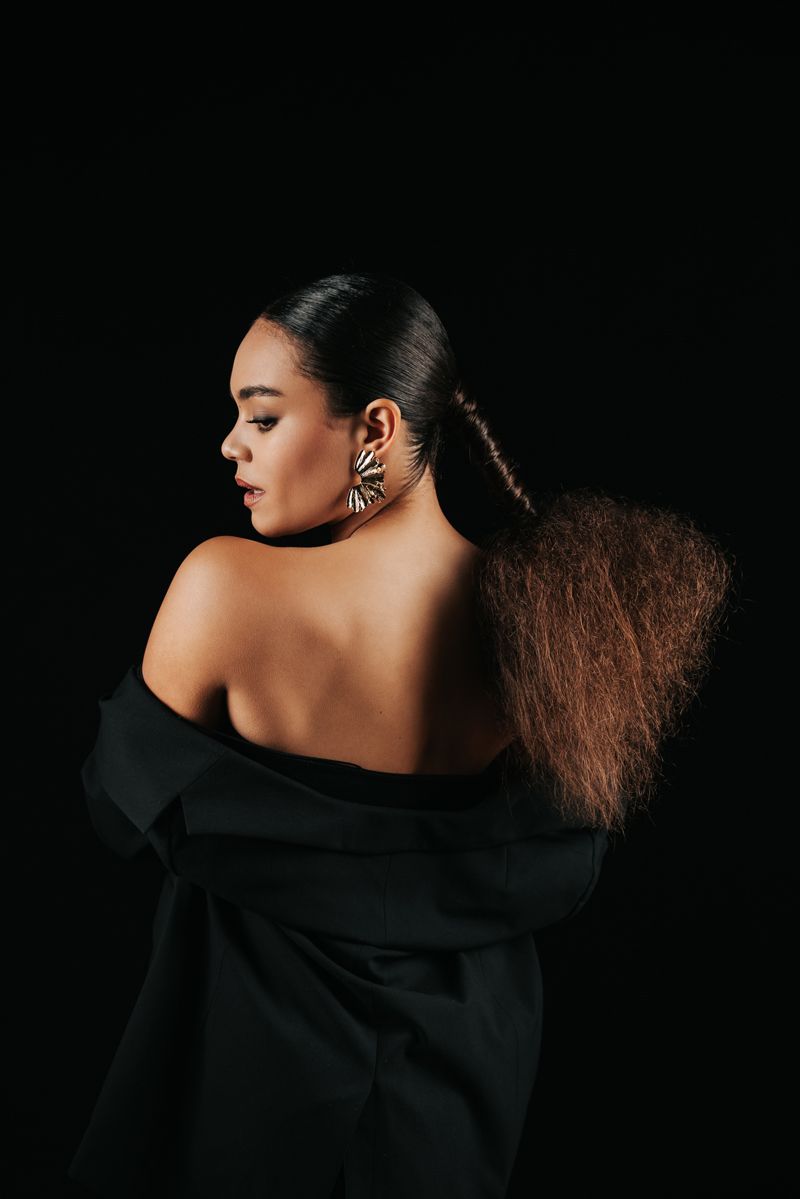 Der Rücken einer Frau mit schwarzem Hemd und Ohrringen.