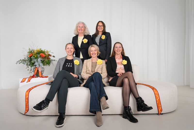 Eine Gruppe von Frauen posiert auf einem Sofa sitzend für ein Foto.