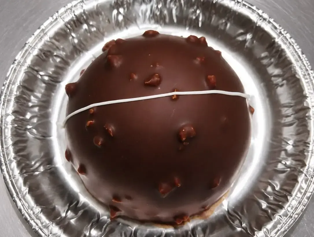 Postre glaseado de chocolate en un molde de aluminio para tarta, decorado con pequeñas chispas de chocolate
