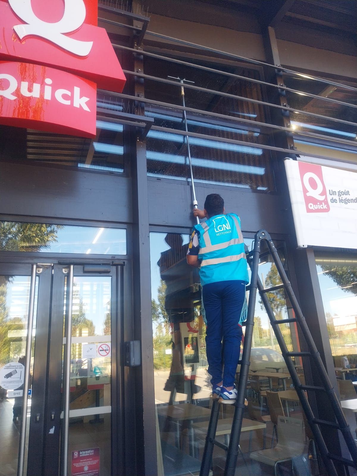 Une personne qui nettoie une façade d'une entreprise