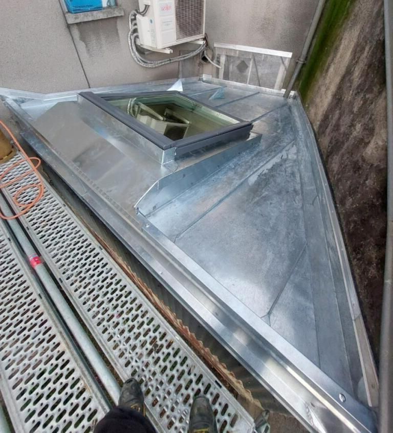 Étanchéité en zinc autour d'une fenêtre de toit.