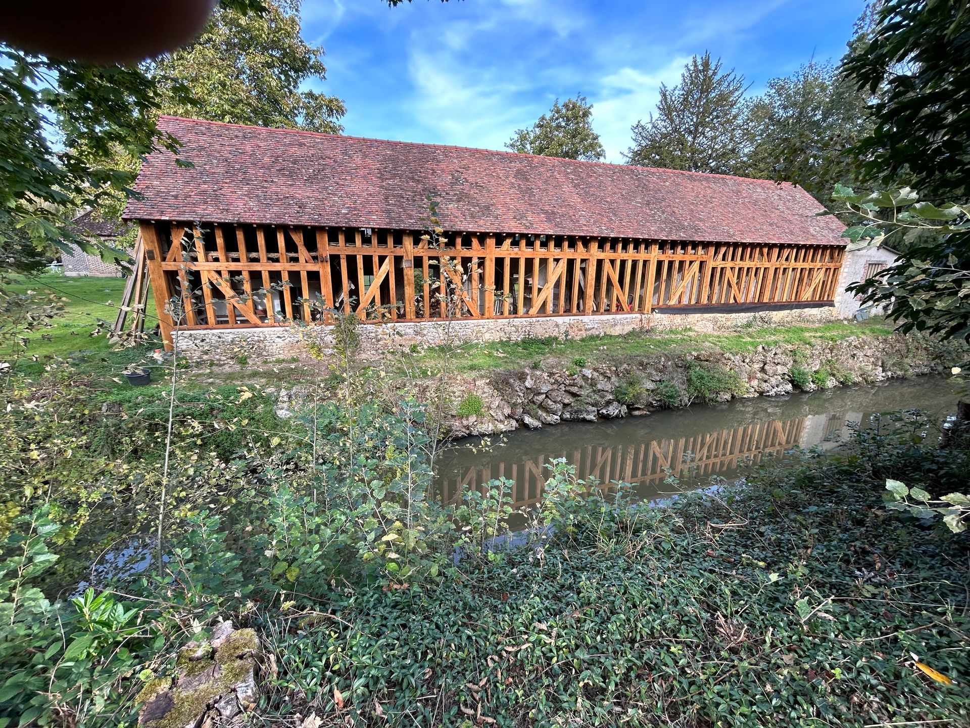 Hangar près de l'eau avec une charpente apparente.