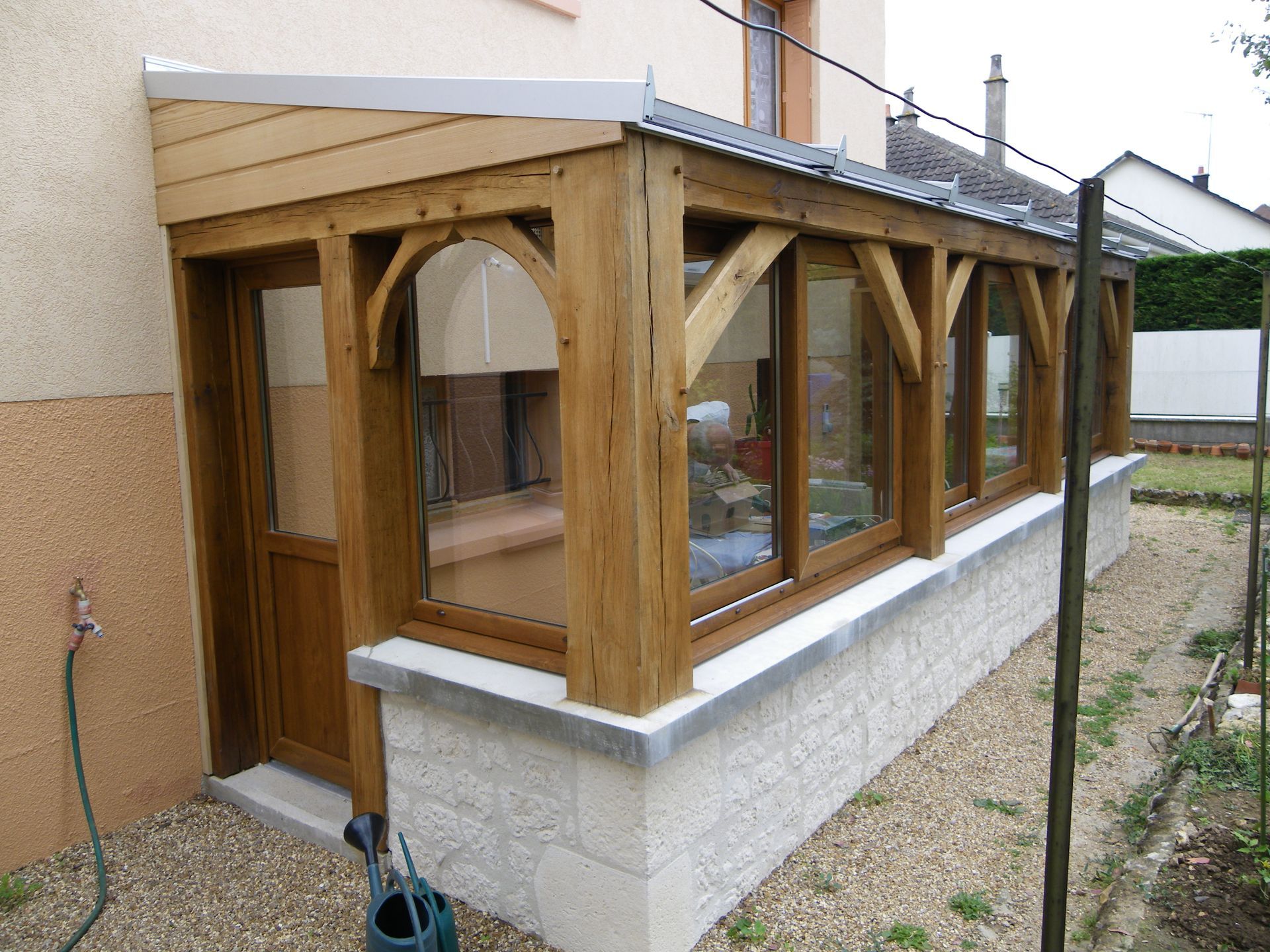 Véranda avec charpente en bois.