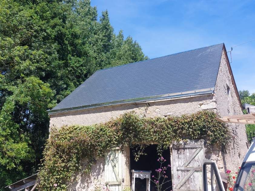 Une maison en pierre avec de la verdure.