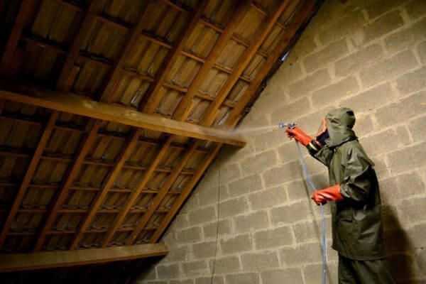 Un homme utilise un traitement sur une charpente.