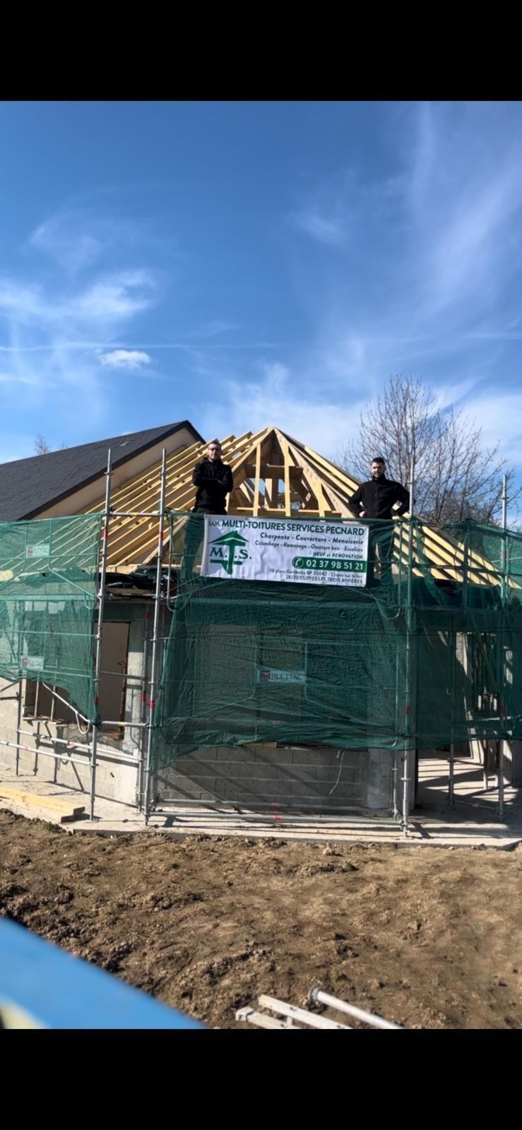 Deux artisans sur une toiture en construction.