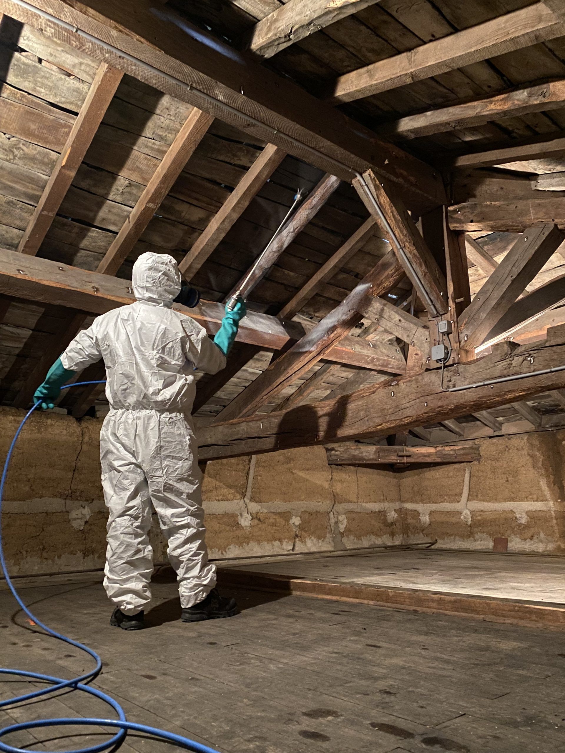 Un homme en vêtement de protection effectue du traitement de charpente.