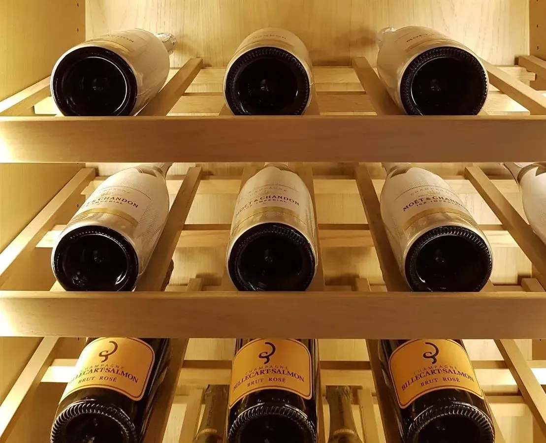 Las botellas de vino están alineadas en un estante de madera.