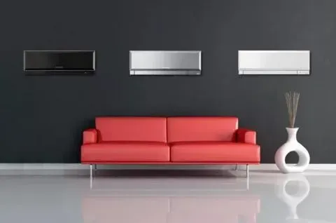 Una sala de estar con un sofá rojo y tres aparatos de aire acondicionado en la pared.