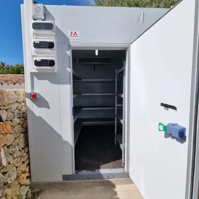 Un edificio blanco con una puerta abierta y estantes en él.