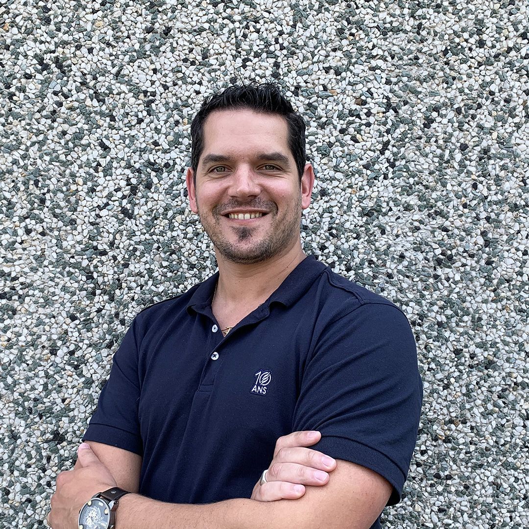 Un homme souriant, vêtu d'un polo bleu marine