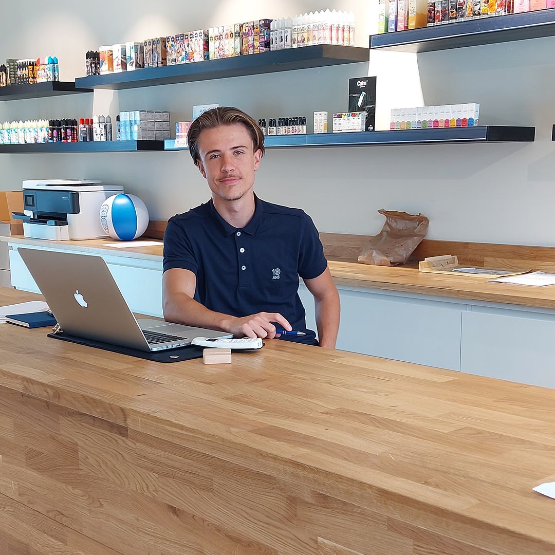 Un homme se tient debout derrière un ordinateur portable à un comptoir 