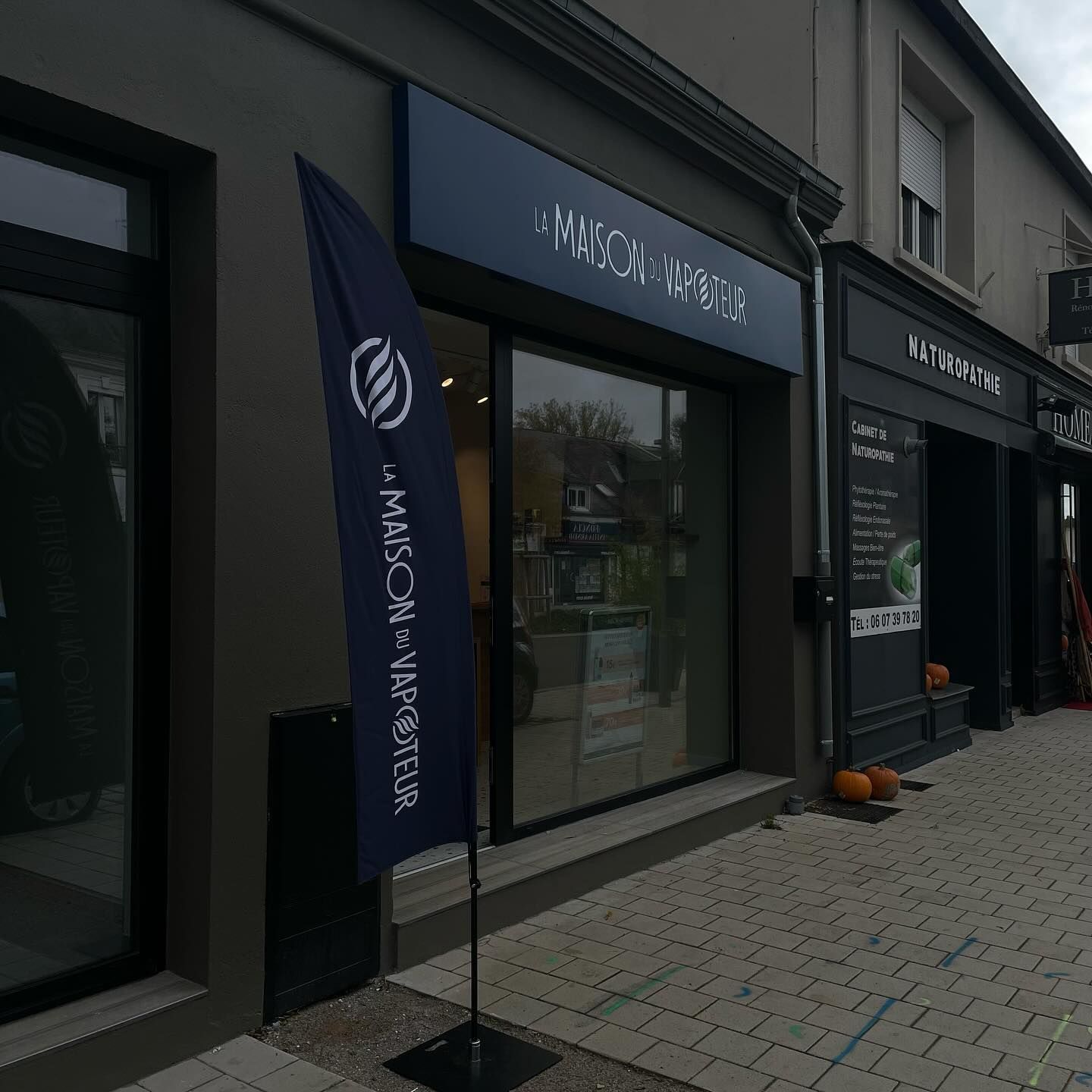 Façade de magasin avec une enseigne bleu foncé sur un trottoir