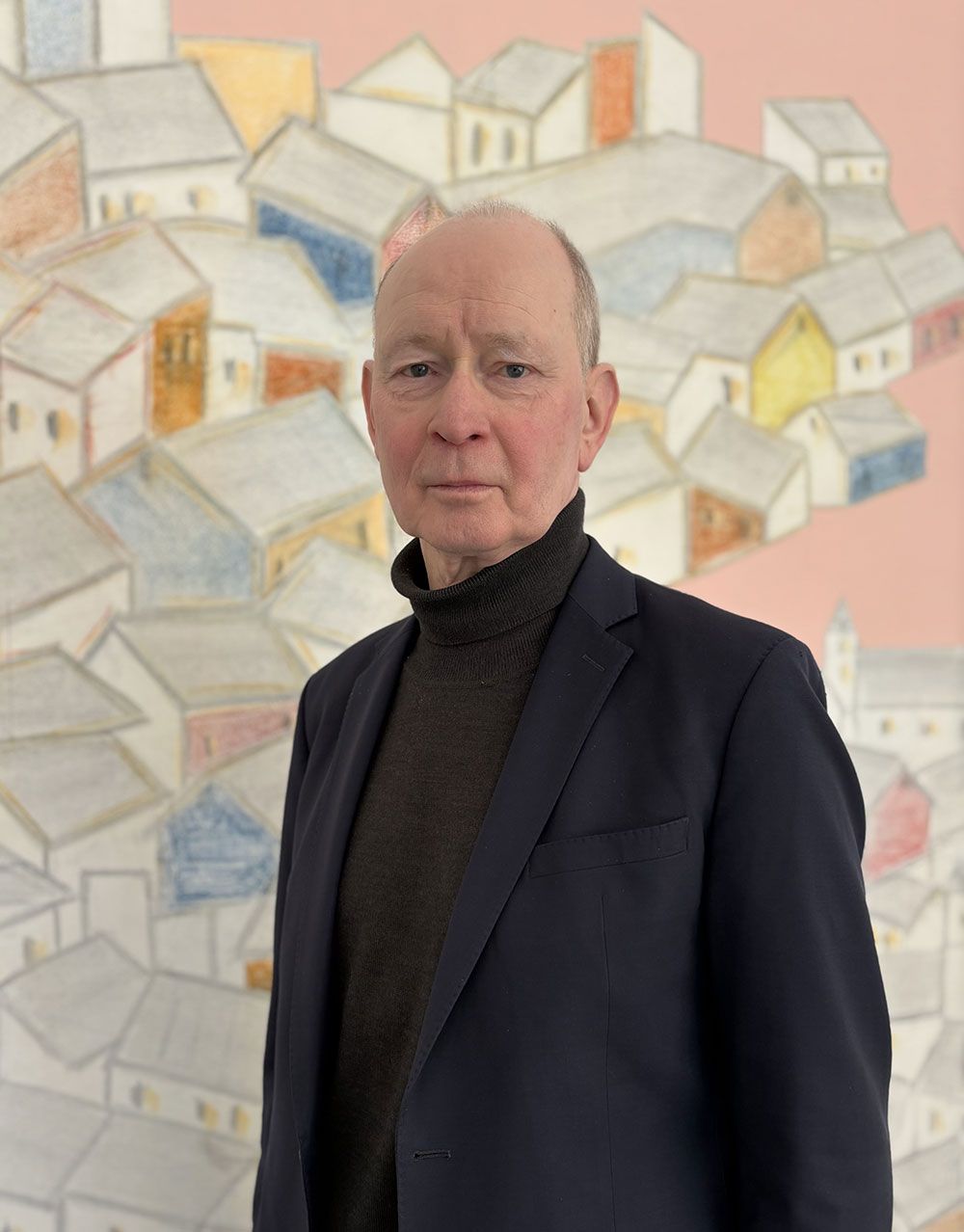 Ein Mann im Anzug steht vor einem Gemälde von Häusern